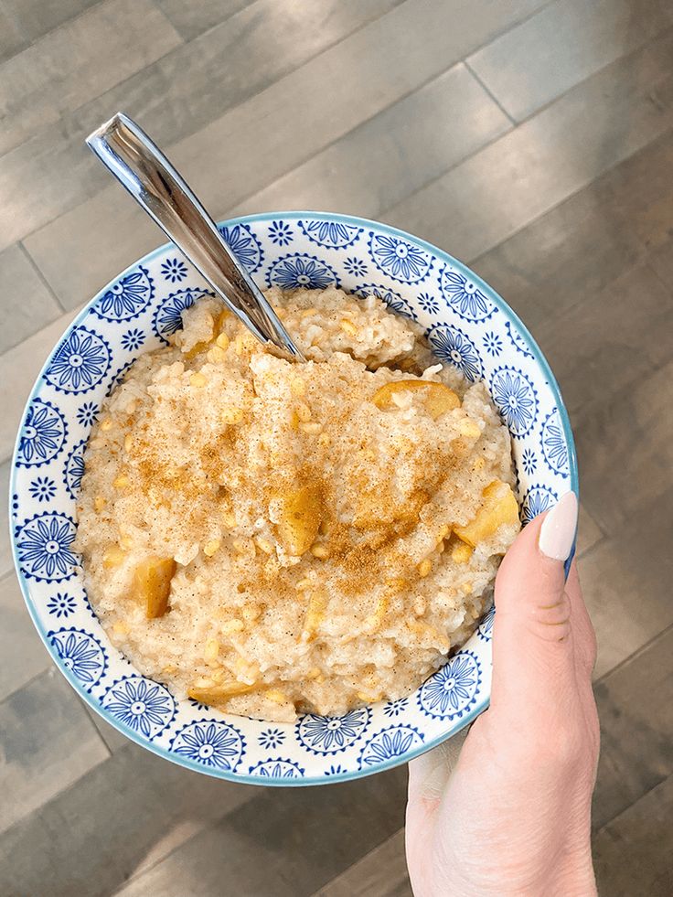 a hand holding a bowl of oatmeal with two spoons in it