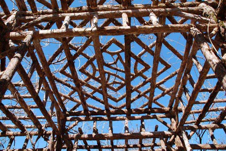 an old wooden structure with birds perched on it's sides and the sky in the background