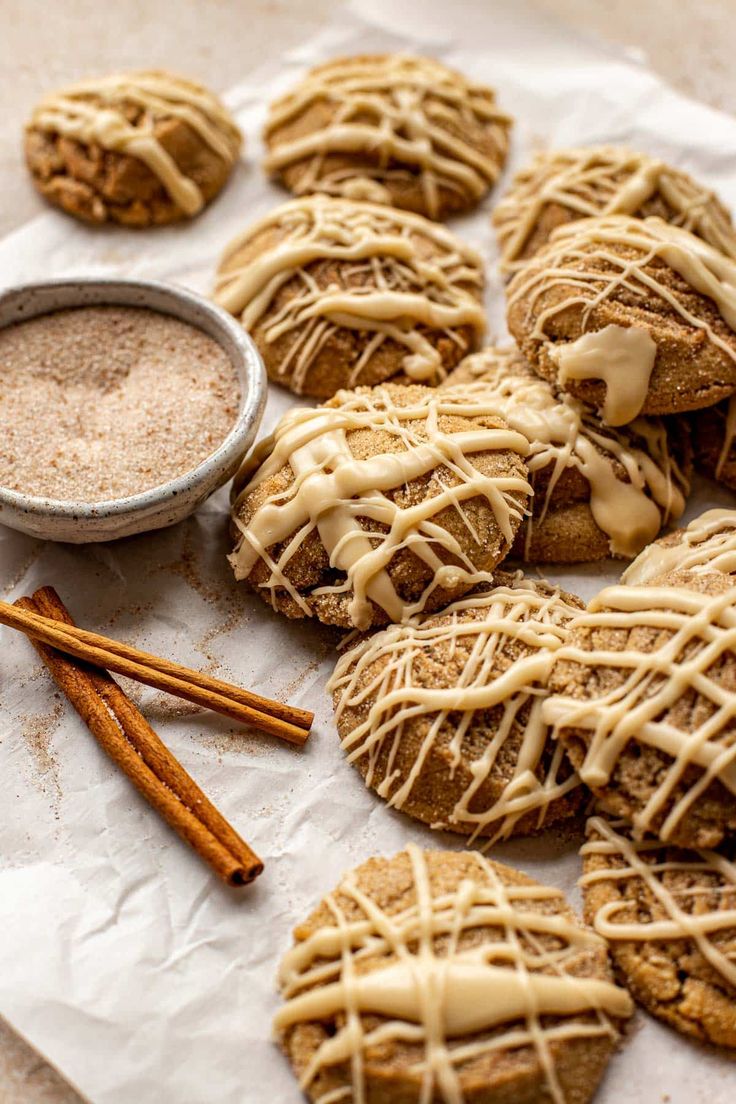 some cookies with icing and cinnamon sticks next to it on a piece of paper