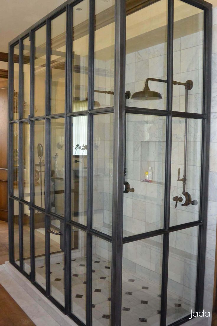 a bathroom with glass walls and tile flooring in the shower area is seen from across the room