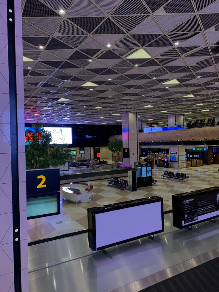 an empty airport terminal with two televisions on either side of the baggage claim area