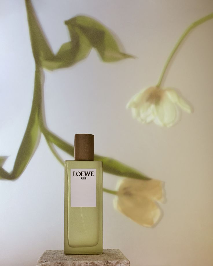 a bottle of lotion sitting on top of a stone block next to a flower