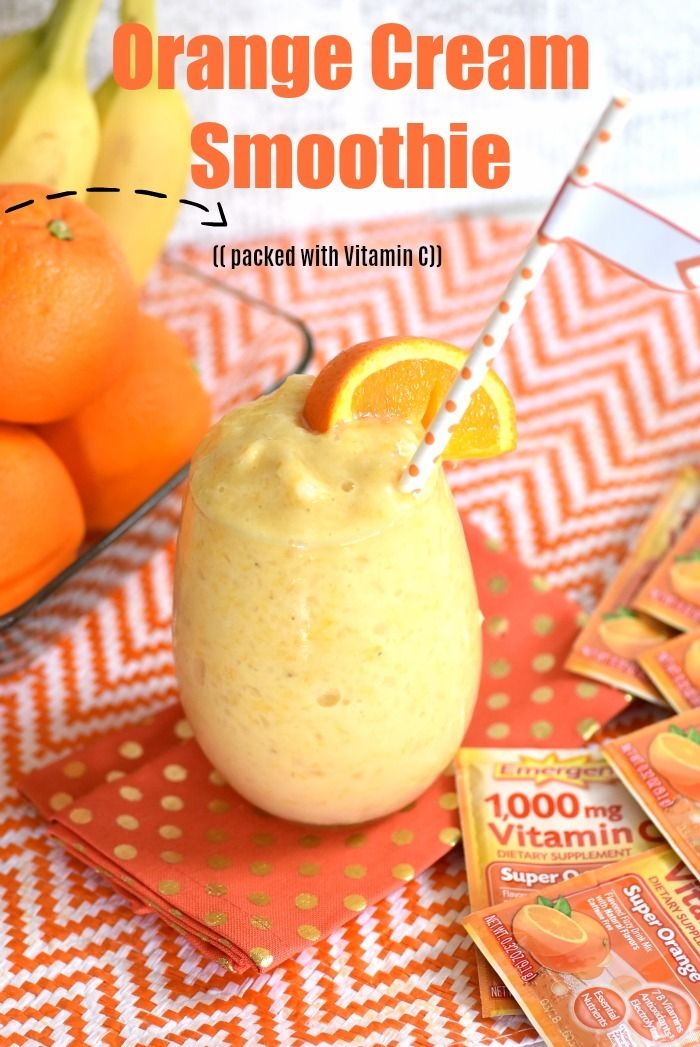 an orange cream smoothie with vitamins on the table next to bananas and oranges