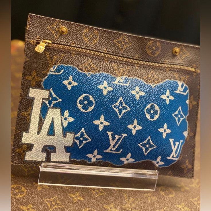 Custom Painted Authentic Louis Vuitton Randonne Pouch Can Be Used As Clutch Or Add Hardware To Be Used As A Wristlet Or Shoulder/Crossbody Wear. Measurements: Length: 8.75" Width: .1" Height: 6.6" Perfect For Any Los Angles Dodger Fan! Painted Louis Vuitton, Louis Vuitton Pouch, Dodgers Fan, Los Angles, Louis Vuitton Brown, Louis Vuitton Accessories, Custom Painted, Custom Paint, Authentic Louis Vuitton