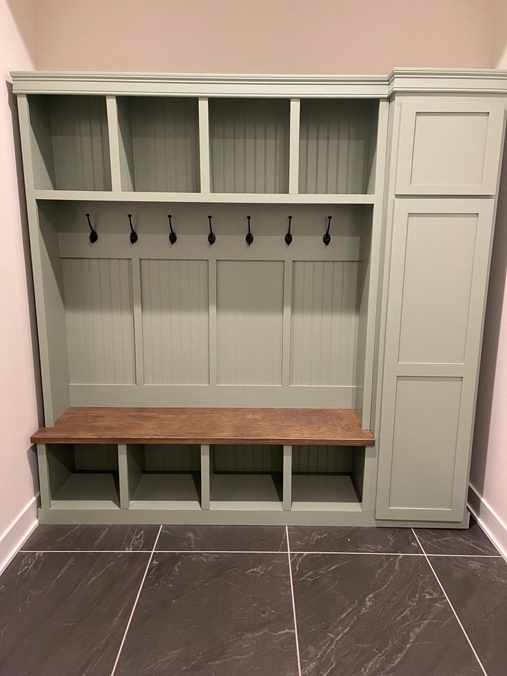 an empty bench in the corner of a room with gray tile flooring and built - in cabinets