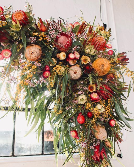 an arrangement of flowers hanging from a window sill