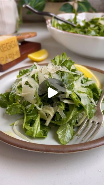 a white plate topped with lettuce and cheese next to a bowl of salad