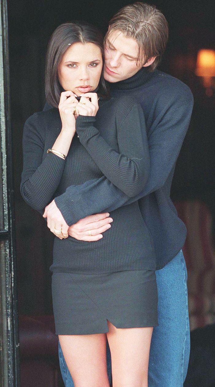 a man and woman standing next to each other in front of a door with their arms around each other