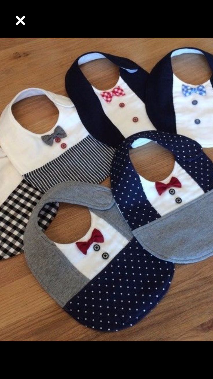 six bibs with bow ties on them sitting on a wooden floor next to each other