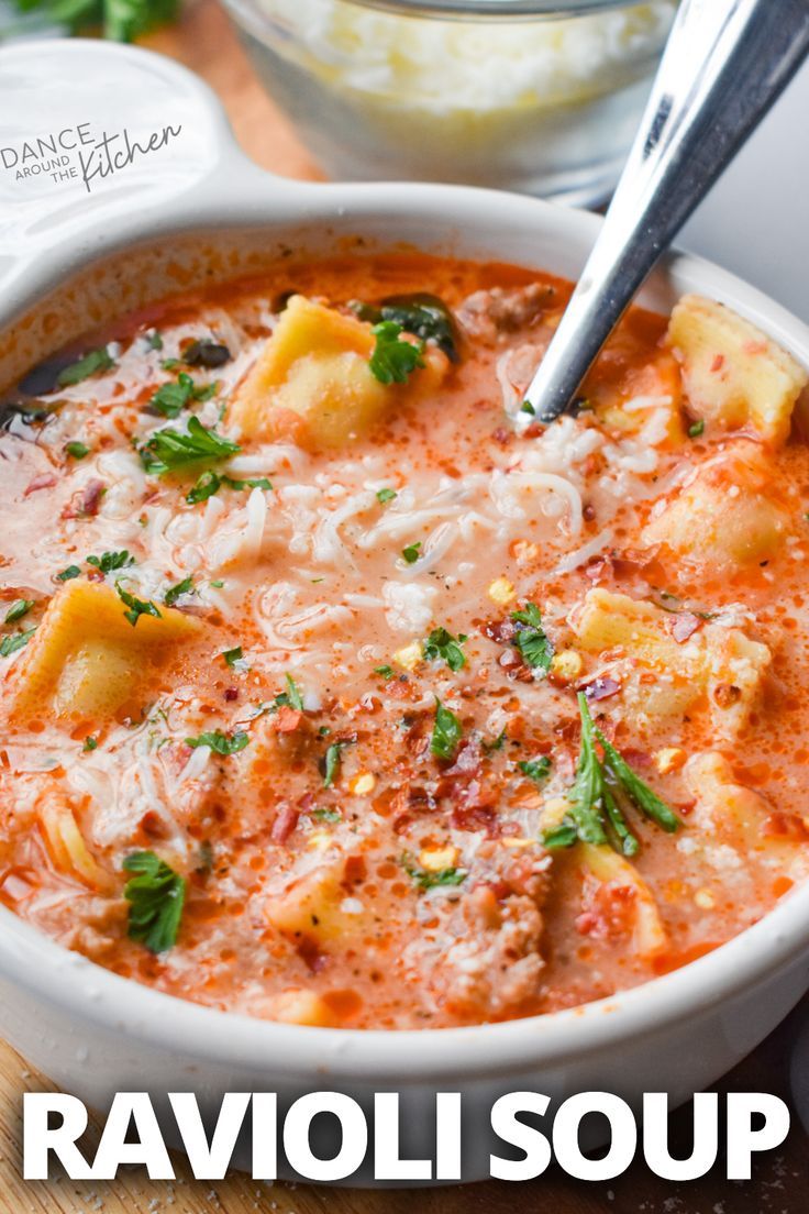 a white bowl filled with ravioli soup on top of a wooden table