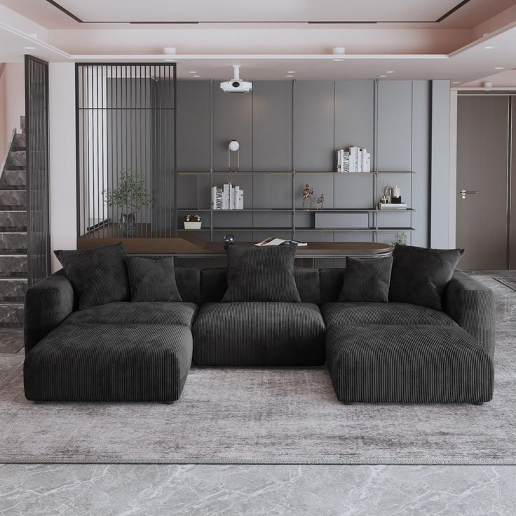 a large gray couch sitting in the middle of a living room next to a staircase