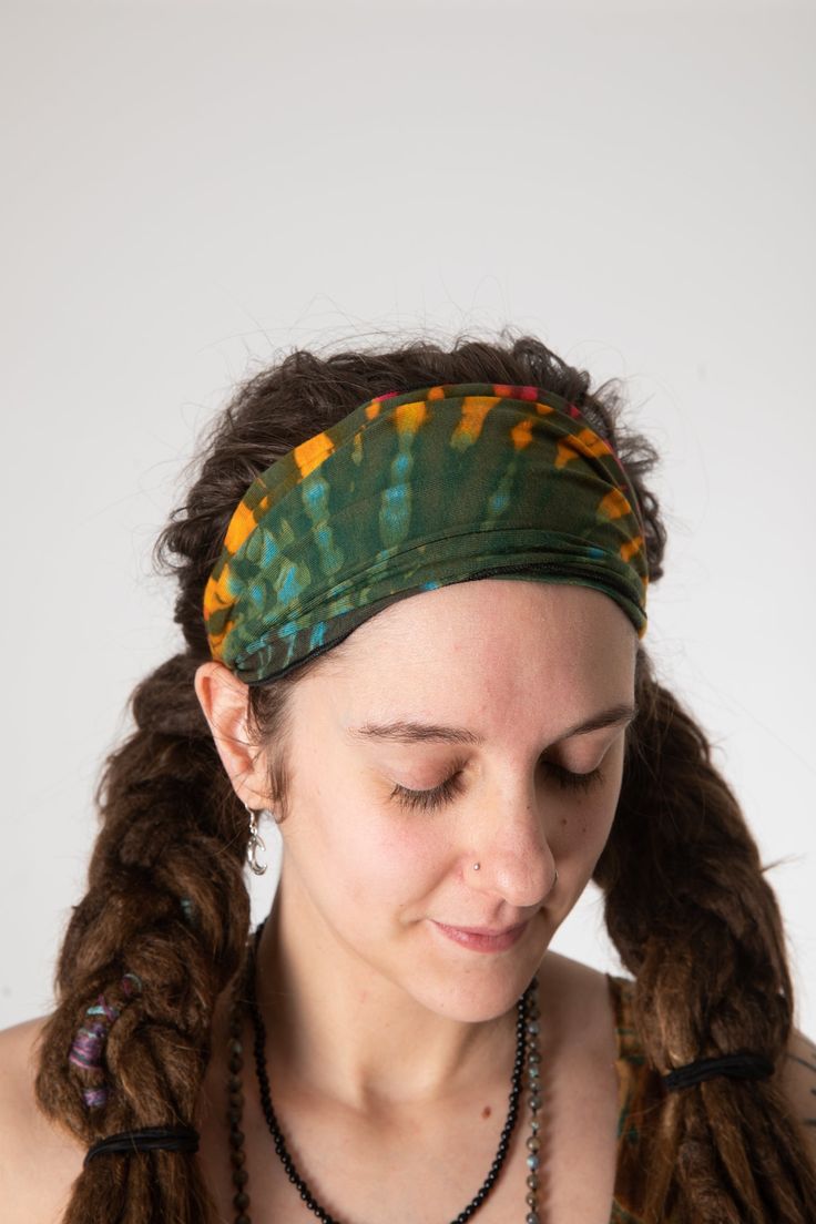 a woman with long hair wearing a green headband and necklace, looking down at her cell phone