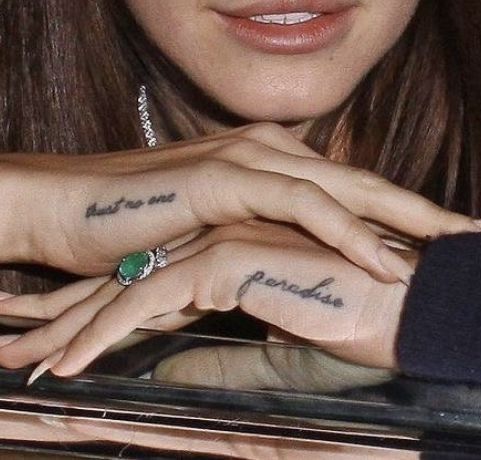 a woman with two tattoos on her fingers