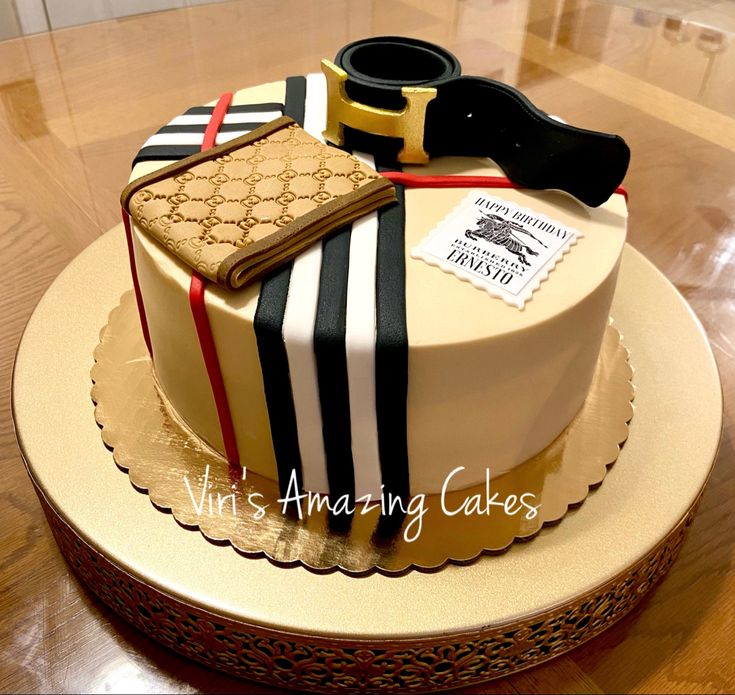 a cake decorated with black, white and gold stripes is on a wooden table next to a pair of scissors