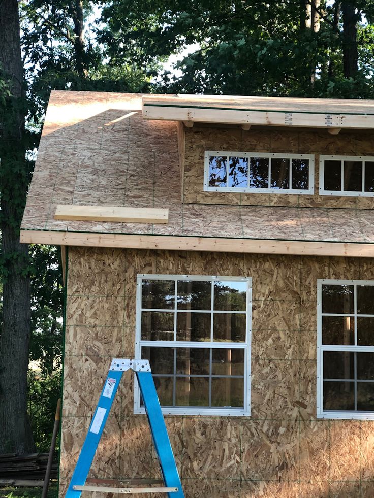 a house being built in the woods with a ladder on it's front porch