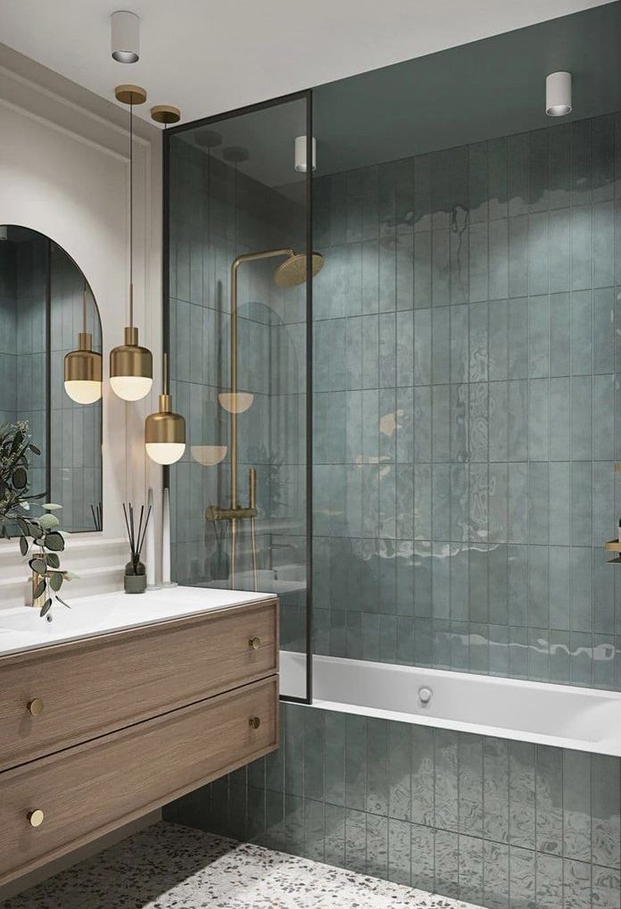 a bathroom with green tile and gold fixtures