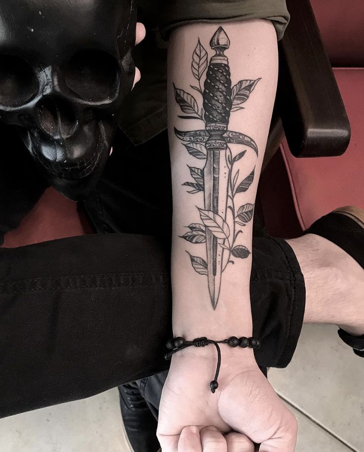 a person with a tattoo on their arm holding a knife in the palm of their hand