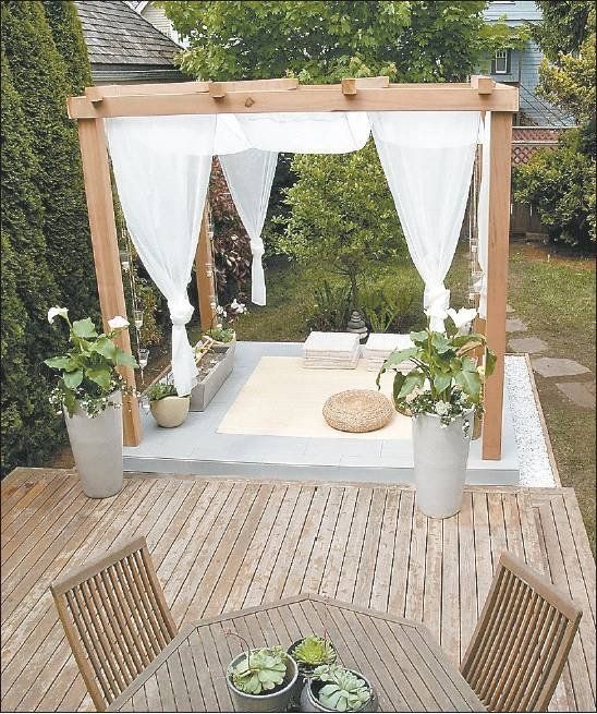 a wooden deck with a table and chairs under a white drape covered gazebo