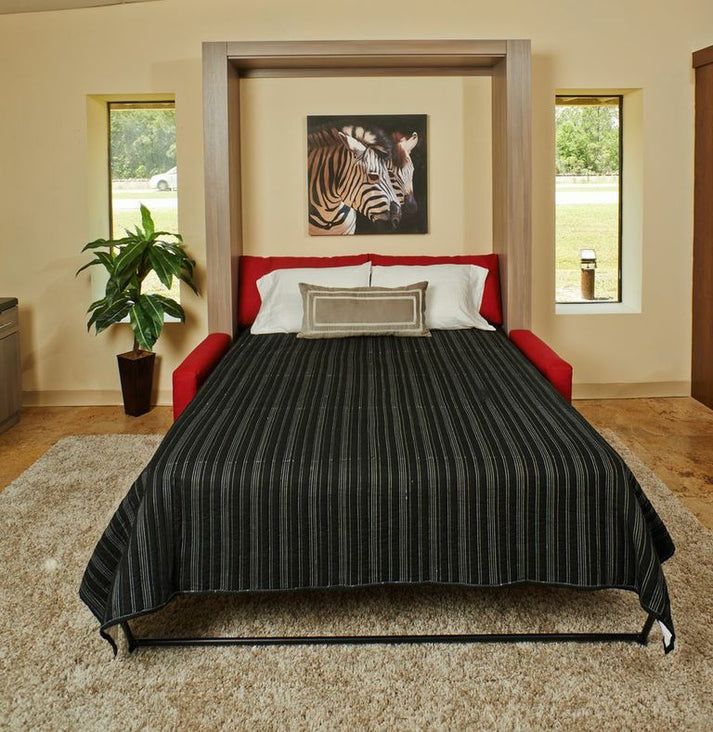 a bedroom with a zebra painting on the wall and a red couch in front of it