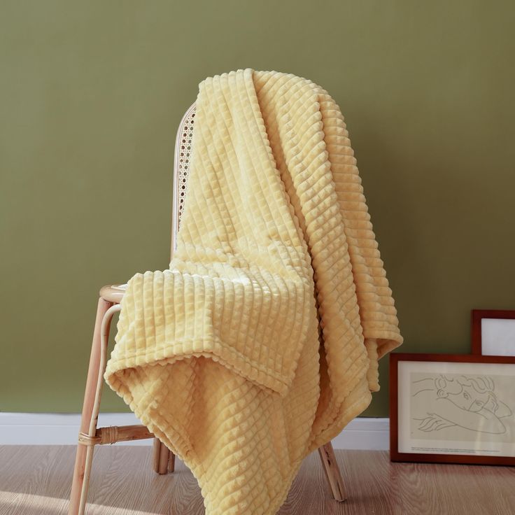 a yellow blanket sitting on top of a wooden chair