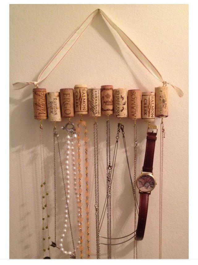 wine corks are hanging on the wall with necklaces and watches attached to it