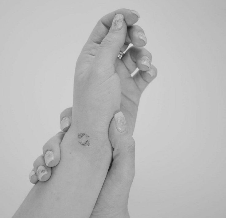 two hands holding each other with tattoos on them