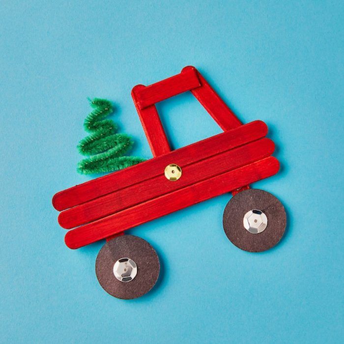 a wooden toy truck with a small christmas tree on the front and wheels attached to it