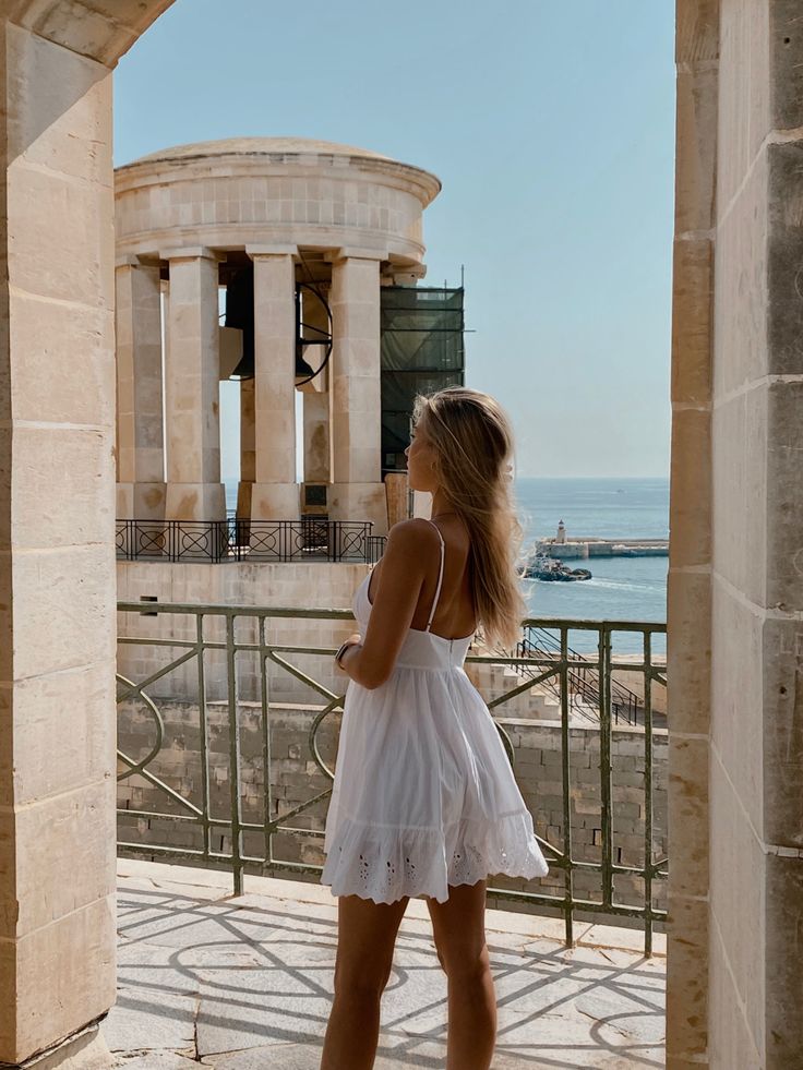 a woman in white dress looking out at the ocean