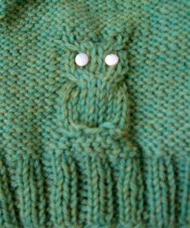 a green knitted sweater with two white buttons