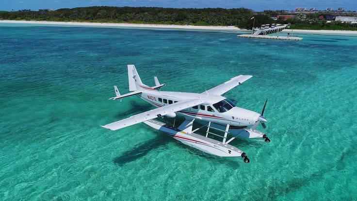 an airplane is flying over the water in clear blue waters with white sand and corals