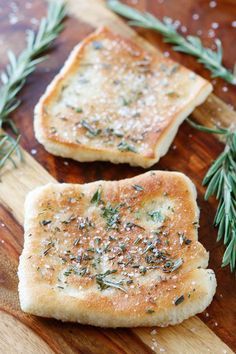 two pieces of bread with herbs on them sitting on a cutting board next to some salt and pepper