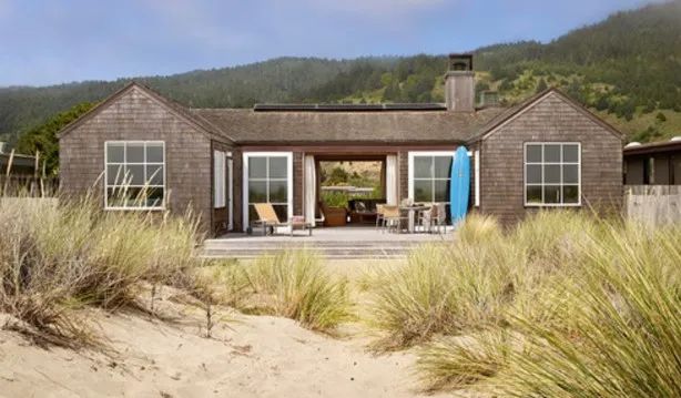 the house is surrounded by tall grass and sand