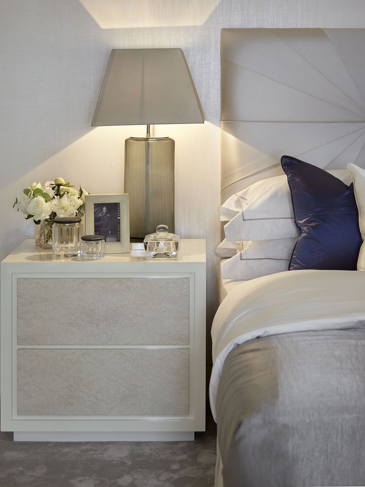 a white bed sitting next to a night stand with two lamps on top of it