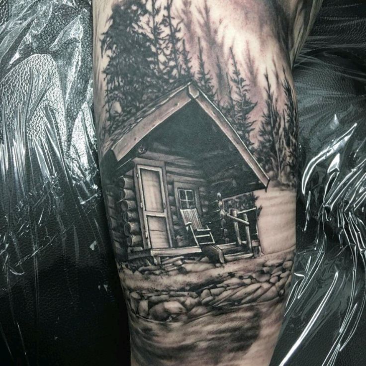 a man's arm with a small cabin tattoo on the side of his leg