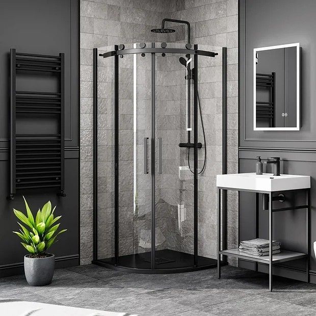 a black and white photo of a bathroom with a sink, shower stall and toilet