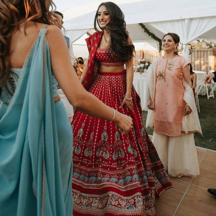 a woman in a red and blue dress is dancing with other people at a wedding