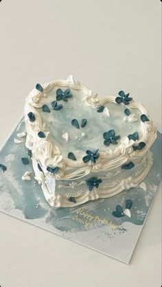 a heart shaped cake with blue flowers on it sitting on a card board in front of a white background