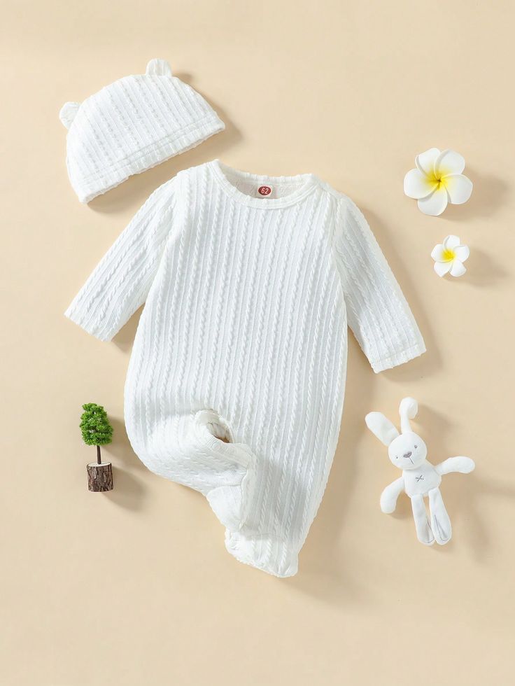 a baby's white outfit, hat and stuffed animal are laid out on the floor