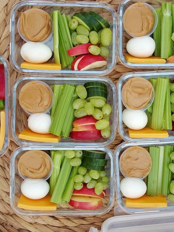 four plastic containers filled with food on top of a woven tablecloth covered flooring