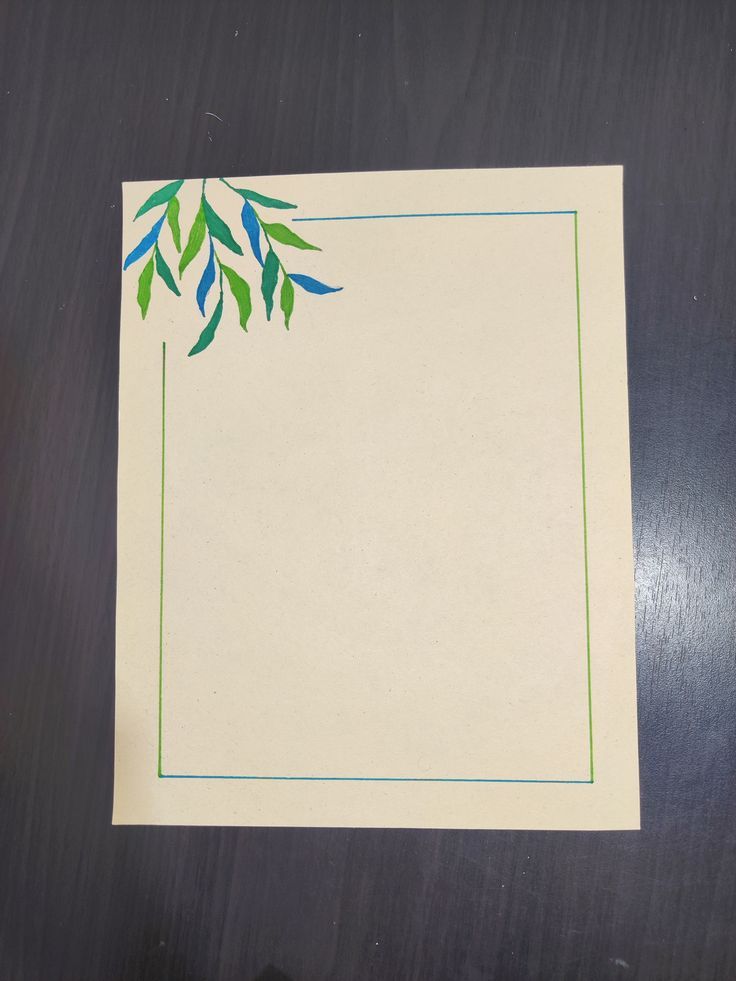 a piece of paper with green and blue leaves on the edge is sitting on a table