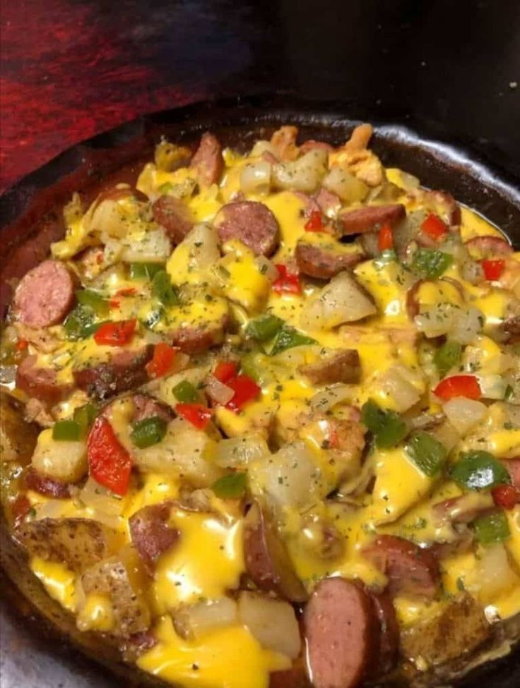 a pizza with sausage, peppers, and cheese on it sitting on a table top