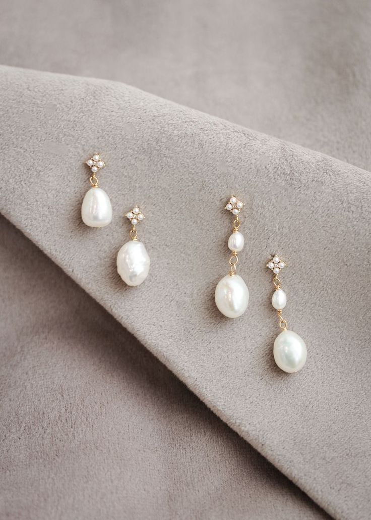 three pairs of pearl and diamond earrings on top of a gray cloth with a white background