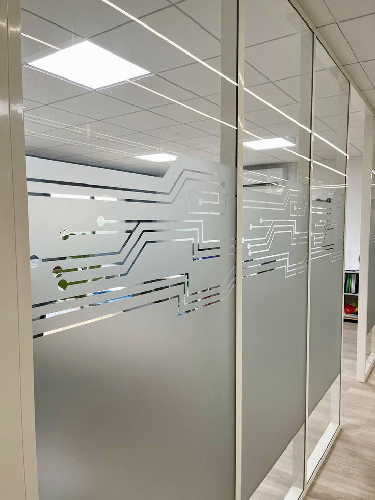 an office cubicle with glass partitions and circuit board graphics on the wall behind it