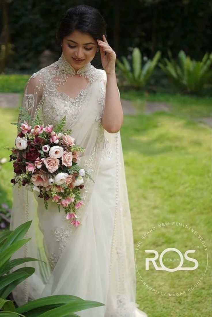 a woman in a white dress is holding a bouquet and posing for the camera with her hand on her head