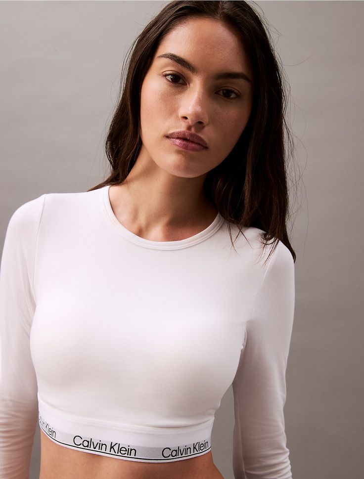 A Calvin Klein icon. This modern cotton t-shirt bralette is the definition of effortless. Cut in a form-fitting silhouette, this bralette is styled with long sleeves and a crewneck. Made with super soft and supple cotton stretch for all day comfort. Designed with the original Calvin Klein logo band, this is a sporty look that feels sexy everyday.  Material: 53% Cotton, 35% Modal, 12% Elastane. Swimwear Suits, Sport Swimwear, Swimwear Outfit, Sporty Look, Shop Swimwear, High Jeans, Wide Leg Jeans, Cotton T Shirt, Sport Outfits