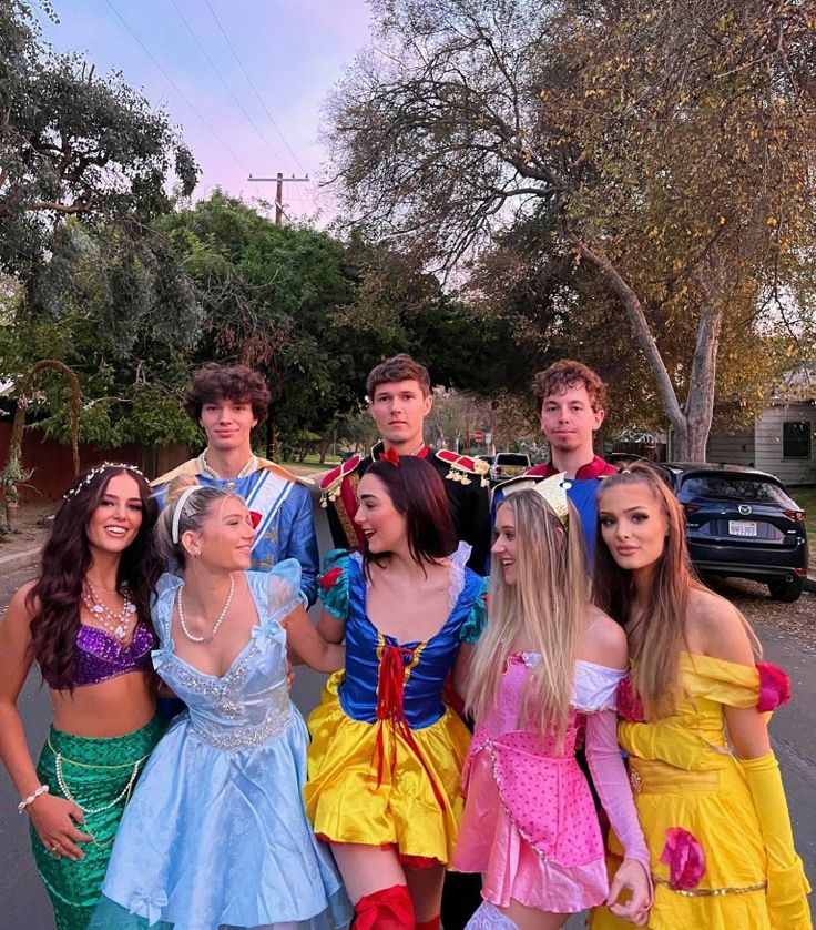 a group of young people standing next to each other on a street with cars in the background