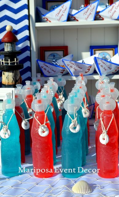 red, white and blue bottles are sitting on a table with paper boats in the background