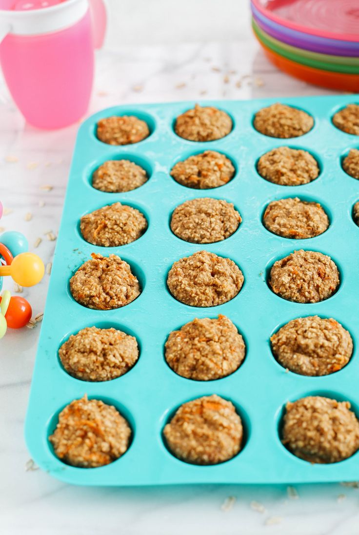 muffins in a blue tray on a table next to colorful bowls and candy