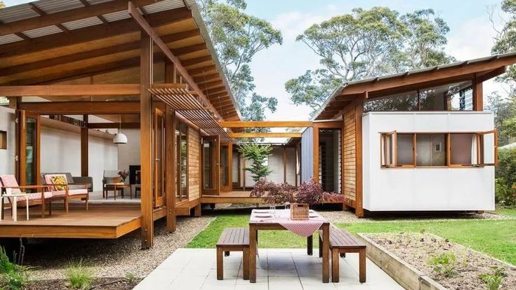 an outdoor patio with tables and chairs next to a house in the woods on a sunny day