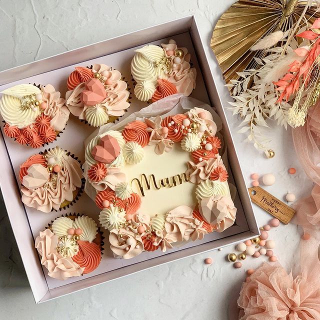 a box filled with cupcakes sitting on top of a table next to flowers